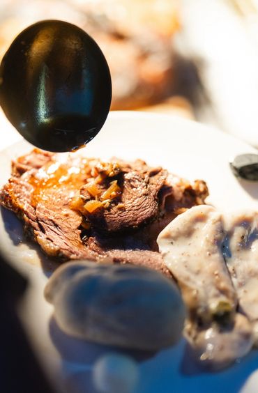 Gravy being poured over a slice of roast beef with mashed potatoes.