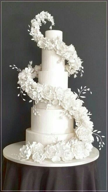 Elegant white tiered cake adorned with cascading floral decorations.