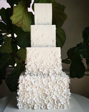 Elegant three-tier white cake adorned with delicate white flowers.