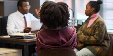 Three people in a discussion in an office.
