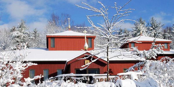 Holy Wisdom church in winter.  Snow on trees, roof and rocks.  Blue sky.
