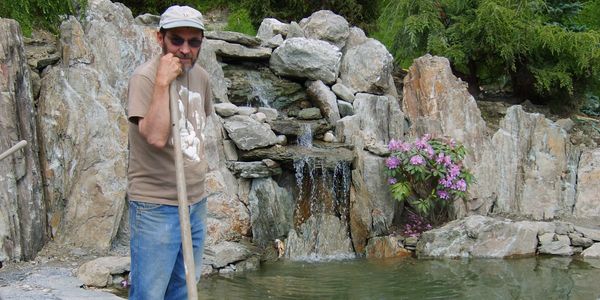 Brother Stavros standing next to water fall in meditation garden, monks monastery