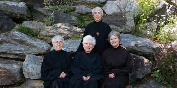 Nuns of New Skete sitting on rock wall next to their monastery