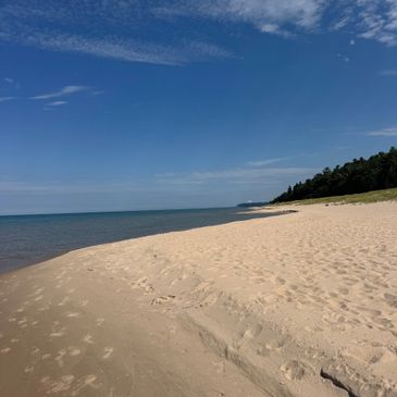 A serene sandy beach with clear blue skies and calm ocean waters.