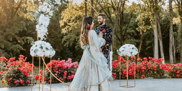 bride and groom taking bridal portraits outdoors in front of their arch
