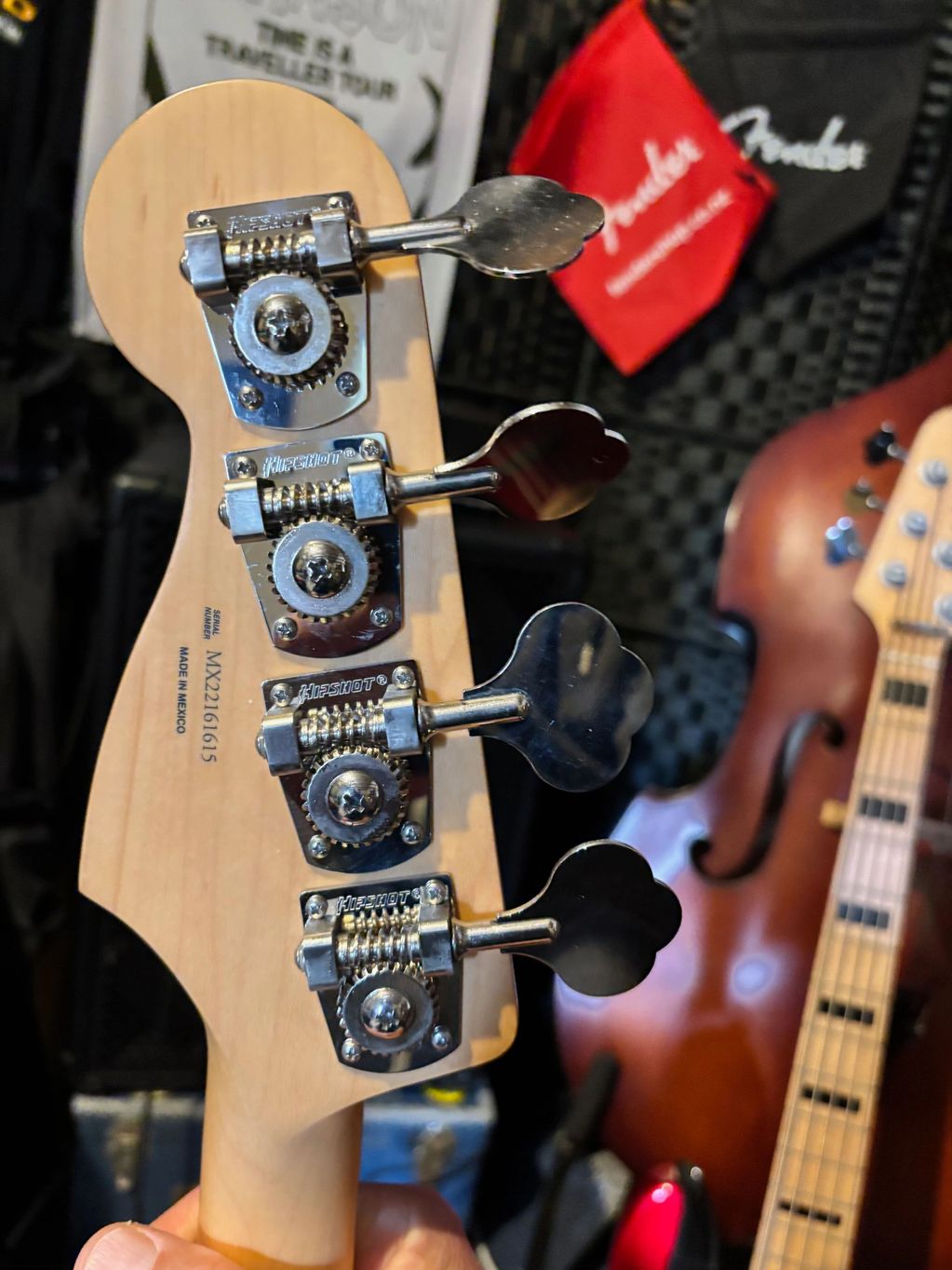 Close-up of a bass guitar headstock with Hipshot tuning pegs and serial number visible.