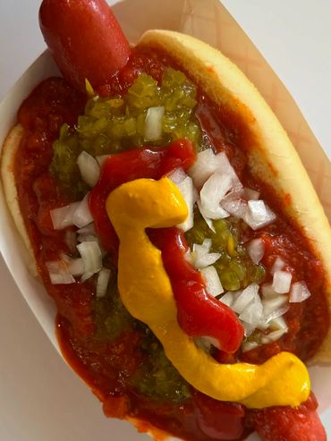 Coney Island up close image featuring hot dog, bun, relish, mustard, onion and Coney Island sauce.