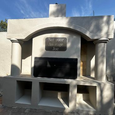 Outdoor grill with a sign saying 'Not your Average Joe' under a clear blue sky.