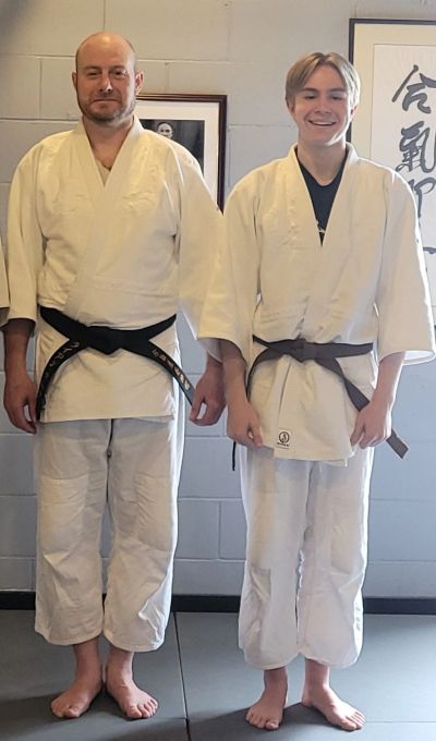 Two martial artists in uniforms with belts standing side by side.