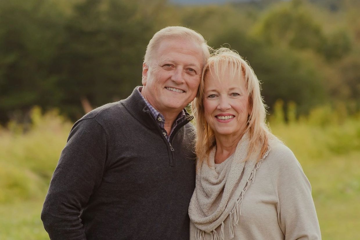 Smiling middle-aged couple outdoors in casual attire.