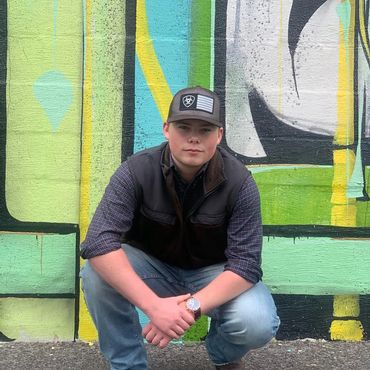 Cameron Sloan sanding outside the graffiti wall in Fort Worth wearing jeans and a baseball cap.