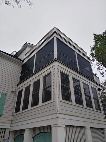 Three-story white house with screened porch at the top.