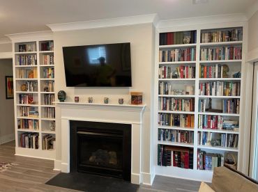 Living room with built-in bookshelves and a TV above a fireplace.