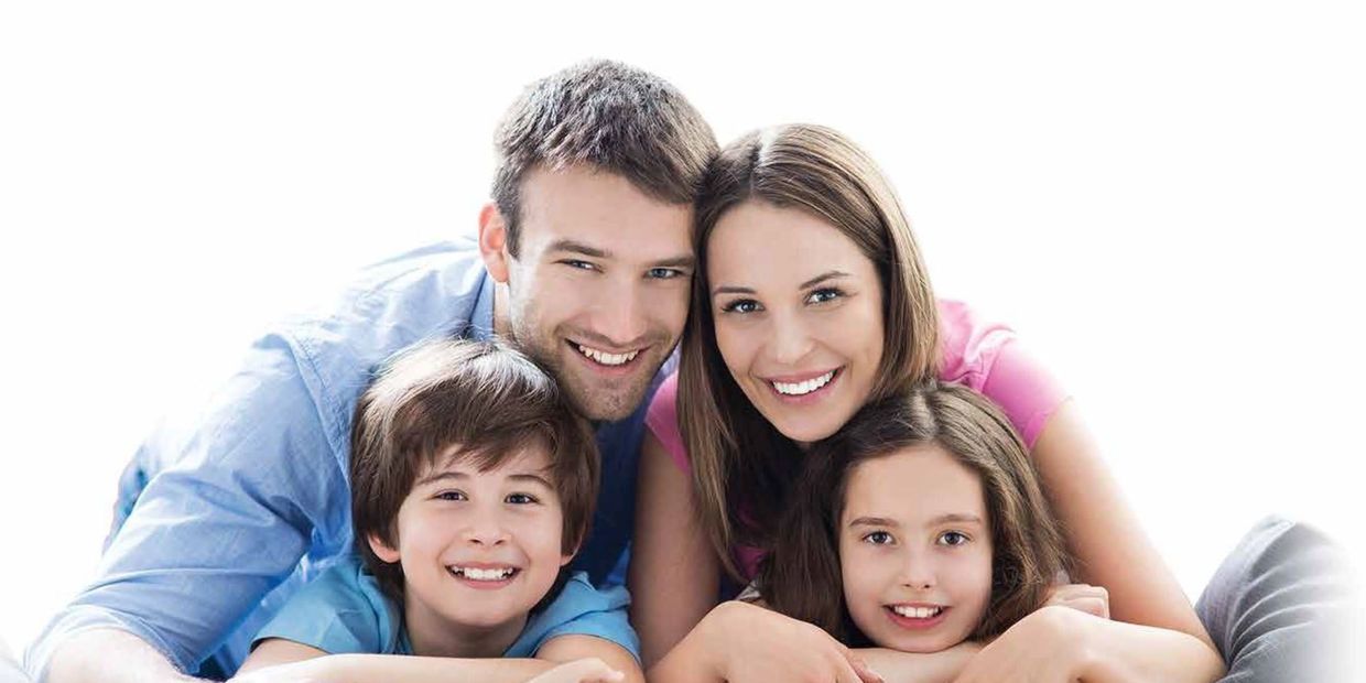 Happy family of four smiling closely together.