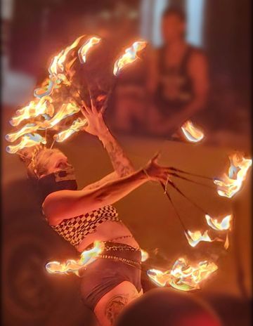 A fire performer manipulates multiple flaming torches in a dynamic pose.