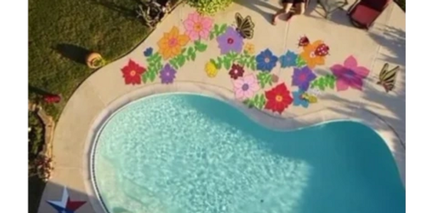 Crystal blue pool with a colorful floral painting that spans the entire length taken from high above
