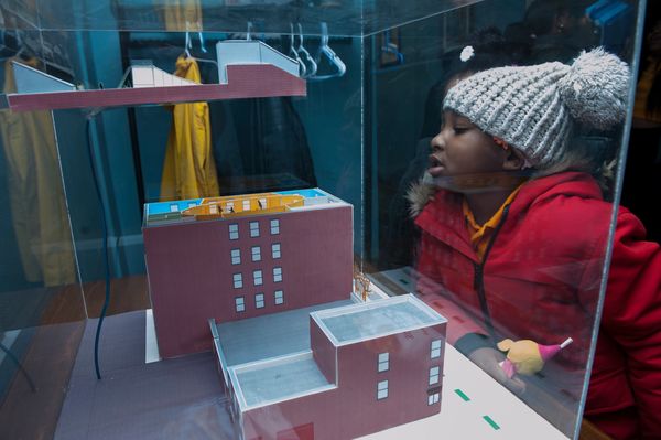 kid looking at a building model in a glass box