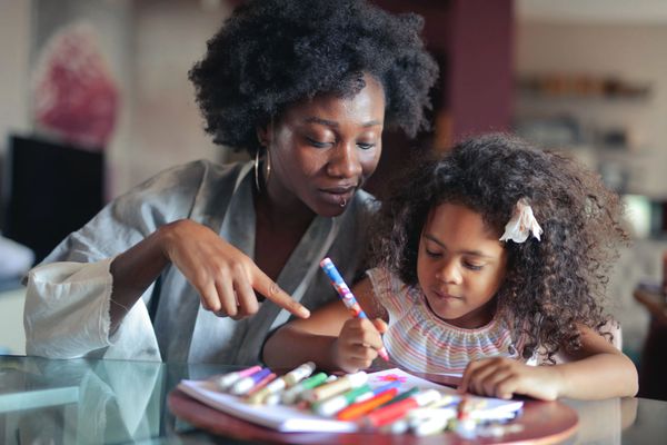 woman teaching a young girl how to write