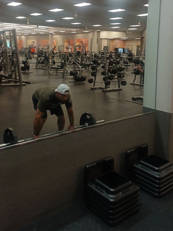 Person lifting weights in a gym mirror.