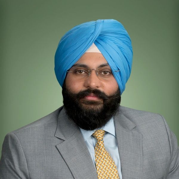 Man wearing blue turban and glasses in suit and tie.
