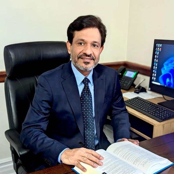 Man in suit sitting at desk with open book.