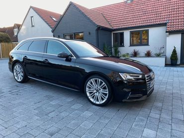 Sleek black Audi station wagon parked in front of a modern house.