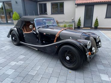 Classic black vintage convertible car with leather interior parked on a paved driveway.