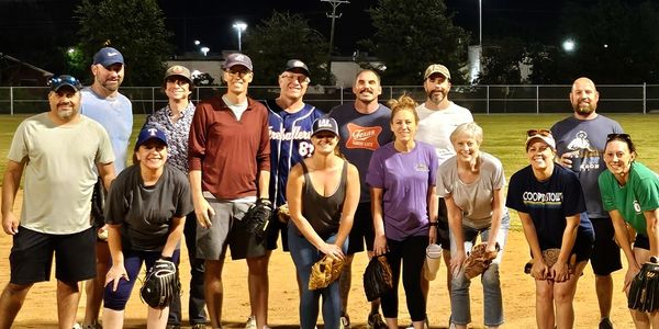 Group of adults after playing 5-Pitch Plucky smiling, enjoying casual competition at baseball field.