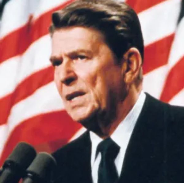 Ronald Reagan speaking in front of American flags.