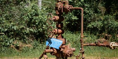 A rusted old brown water heater with a blue sign hanging on it 