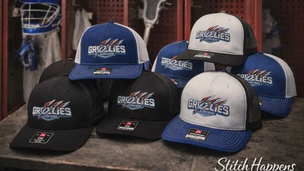 Collection of Grizzlies lacrosse hats in black, blue, and white.