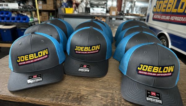 Multiple JOE BLOW branded caps on a table.