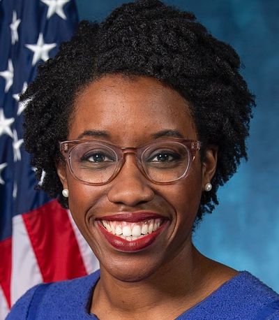 Smiling woman wearing glasses with an American flag in the background.