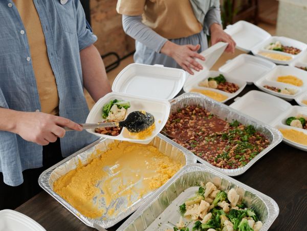 Volunteers serving food in containers.
