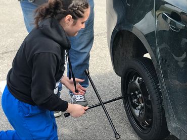 A girl fixing a tire on a car