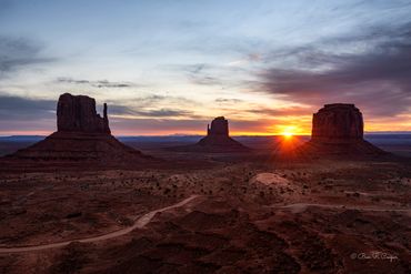 Sunrise in Monument Valley, the sun peeking up over the horizon. West, East and Merrick buttes 