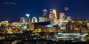 Minneapolis, Minnesota skyline at night with a crescent moon over the city. Deep blues, city lights