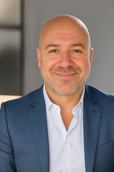 Smiling bald man in a blue suit and white shirt.