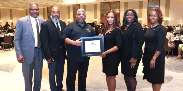 Group posing with award at an event.