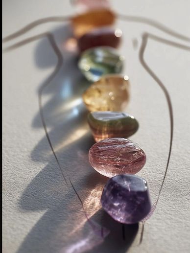 Colorful polished stones aligned on paper with a drawn human figure.