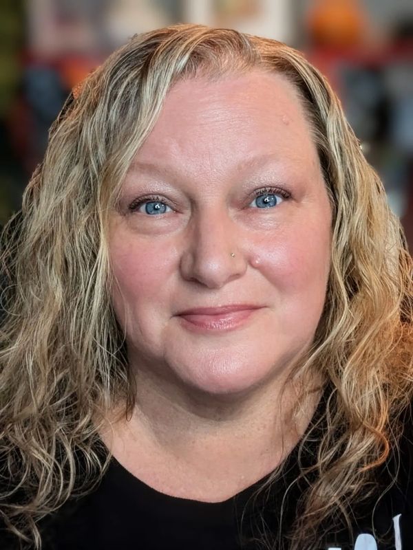 A smiling woman with curly blonde hair and blue eyes.