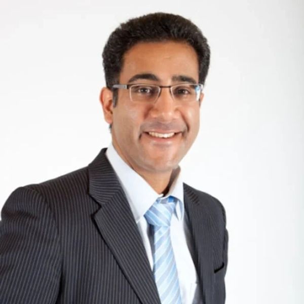 Man in glasses and suit smiling.