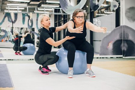 Personal trainer helping female client with workout