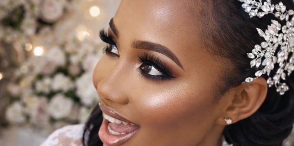 Close-up of a smiling bride with elegant makeup and a sparkling hair accessory.