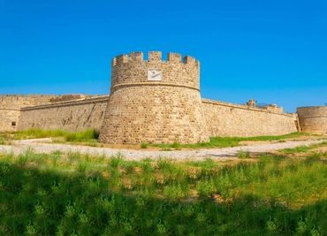 Ancient stone fortress tower under clear blue sky.