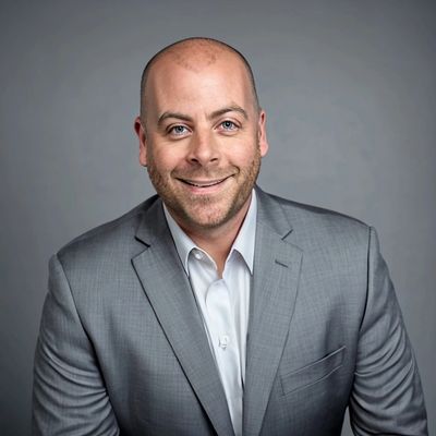 Smiling bald man in a gray suit against a plain background.