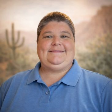 Smiling person in a blue polo shirt with a desert background.