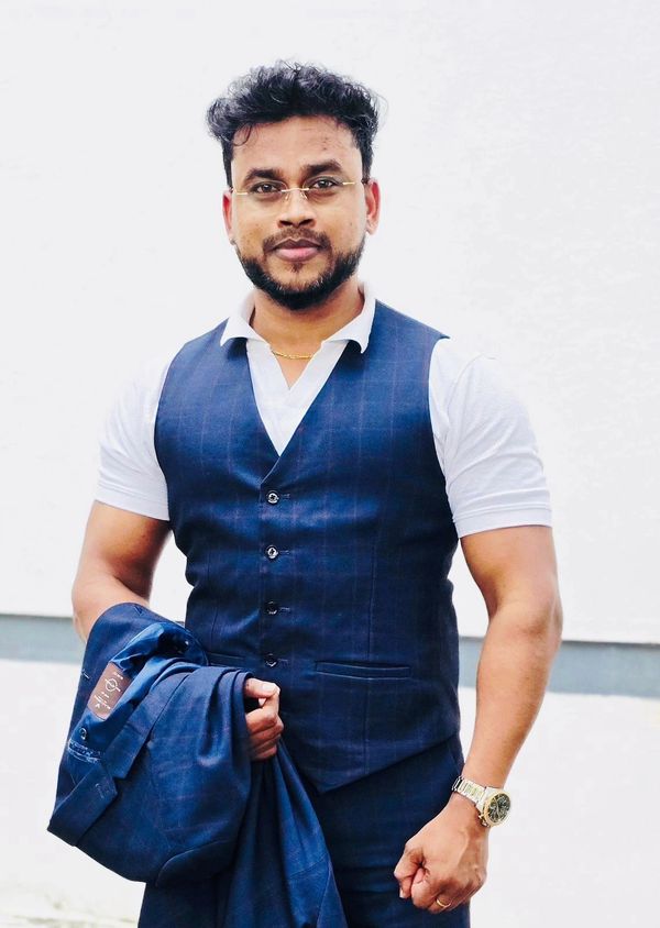 Man in a blue vest and white shirt holding a matching blue jacket.