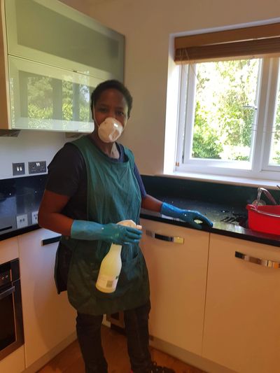 Person cleaning kitchen wearing protective mask and gloves.