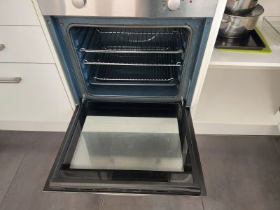 Open modern oven with racks inside.